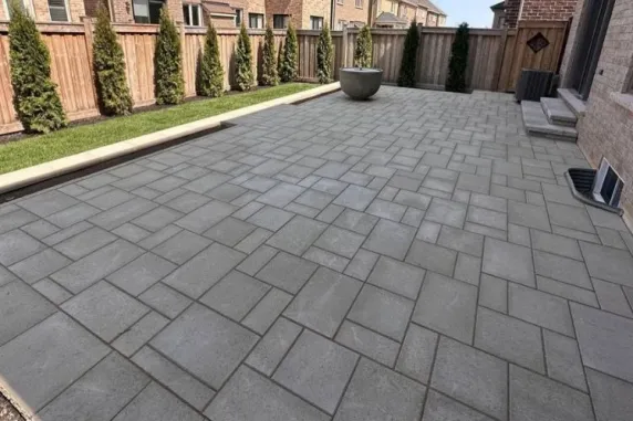 Modern backyard interlocking patio with large concrete pavers in a clean grid layout
