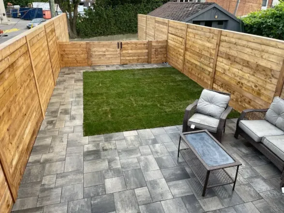 backyard interlocking patio with grass lawn and wood privacy fence with double gate