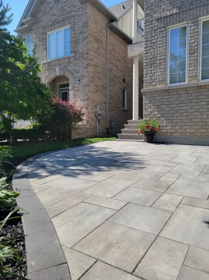 front yard interlocking driveway with curved border clean stone pavers and landscaped entrance