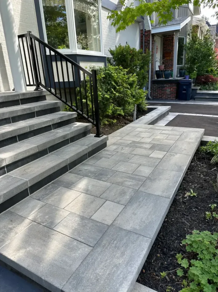 front yard interlocking stone walkway with steps railing and landscaped garden area