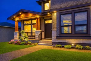 front yard walkway with landscape lighting, lawn and illuminated house entrance at night