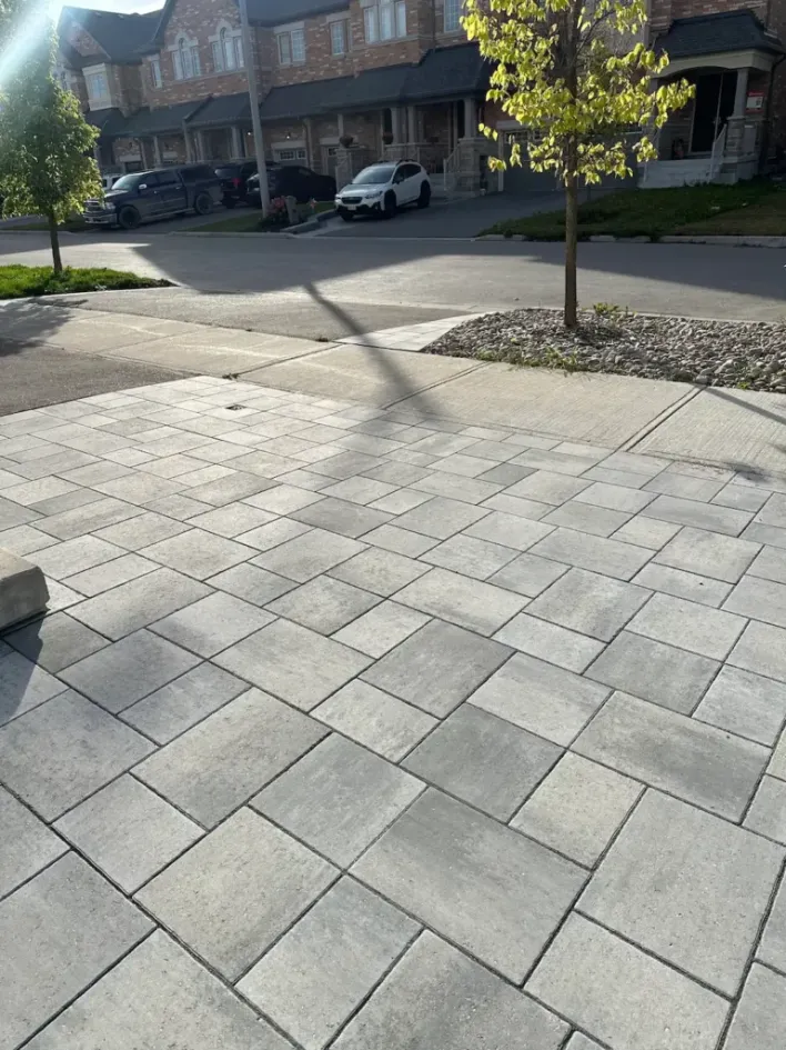 interlocking stone driveway in front yard with clean pattern and residential street view