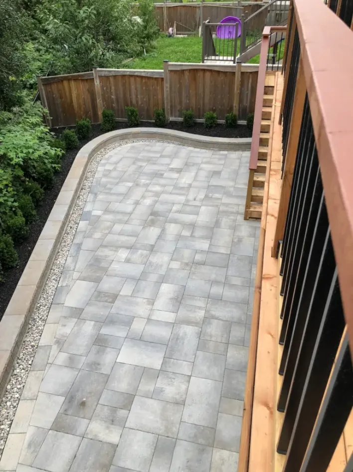 interlocking patio with retaining wall border gravel drainage and landscaped backyard terrace