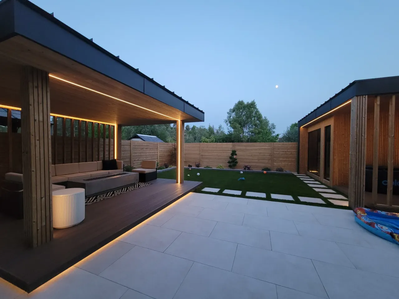 modern backyard patio with pergola seating area sauna structure and landscape lighting
