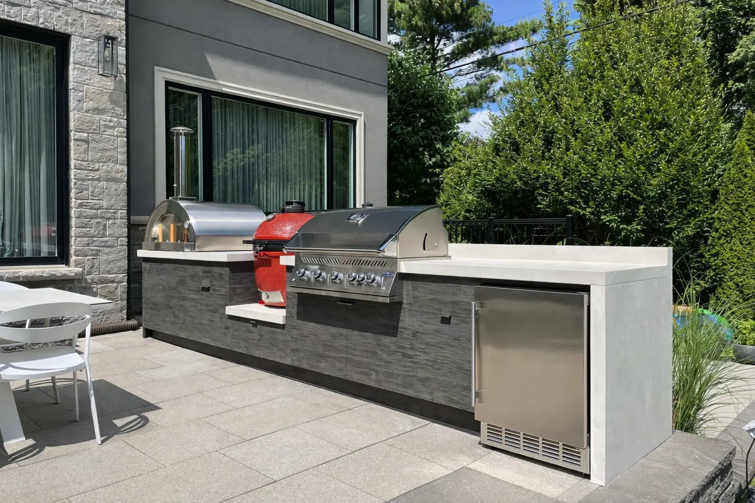 modern outdoor kitchen with built-in grill, pizza oven and stainless steel appliances on patio
