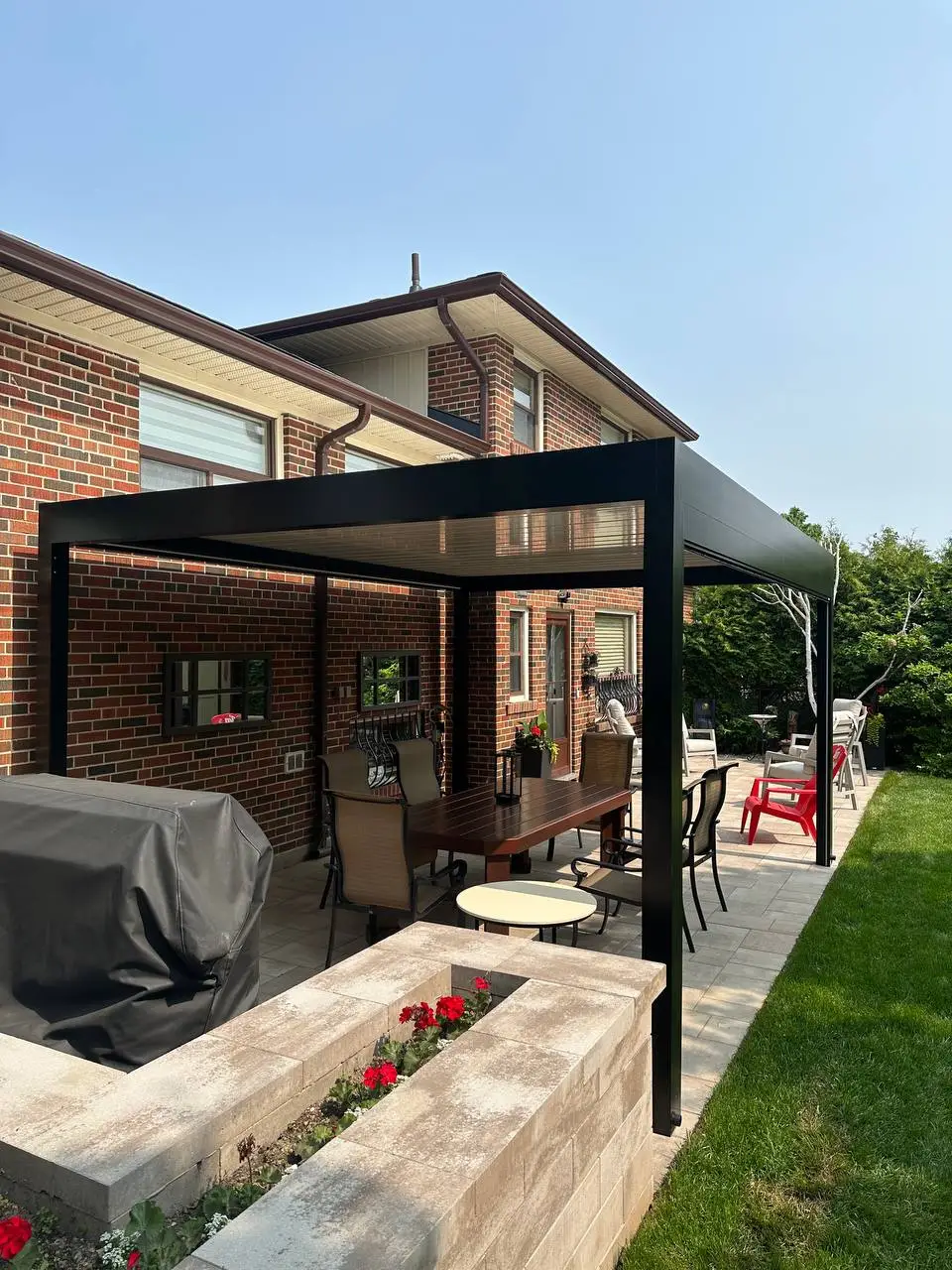 attached modern pergola over patio dining area with black frame and outdoor seating