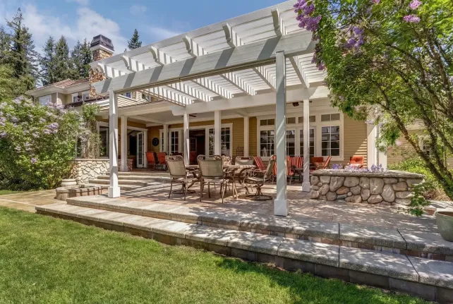 backyard patio with white pergola, stone base and outdoor dining seating area