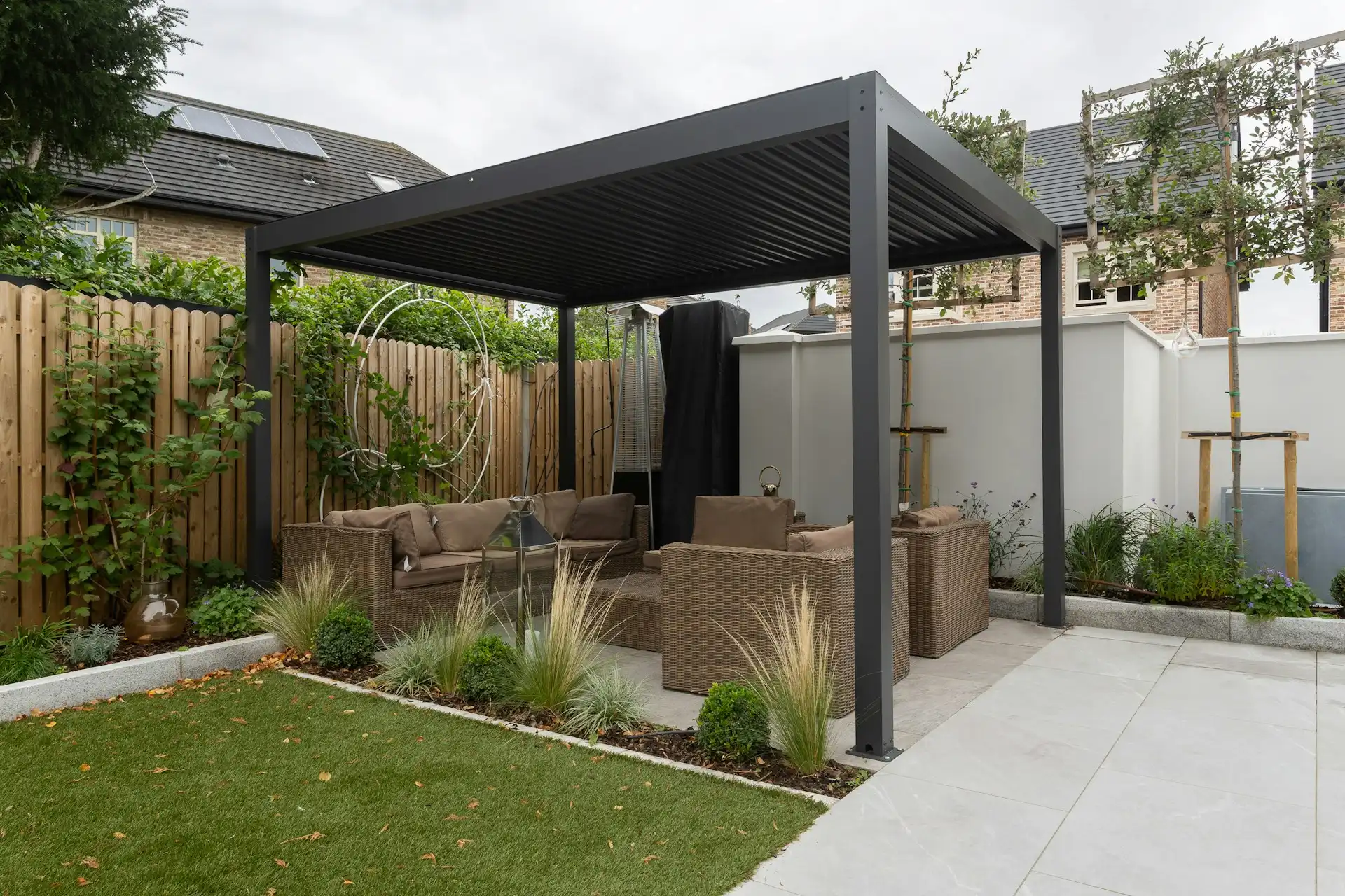 freestanding aluminum pergola with louvered roof and outdoor lounge seating in backyard
