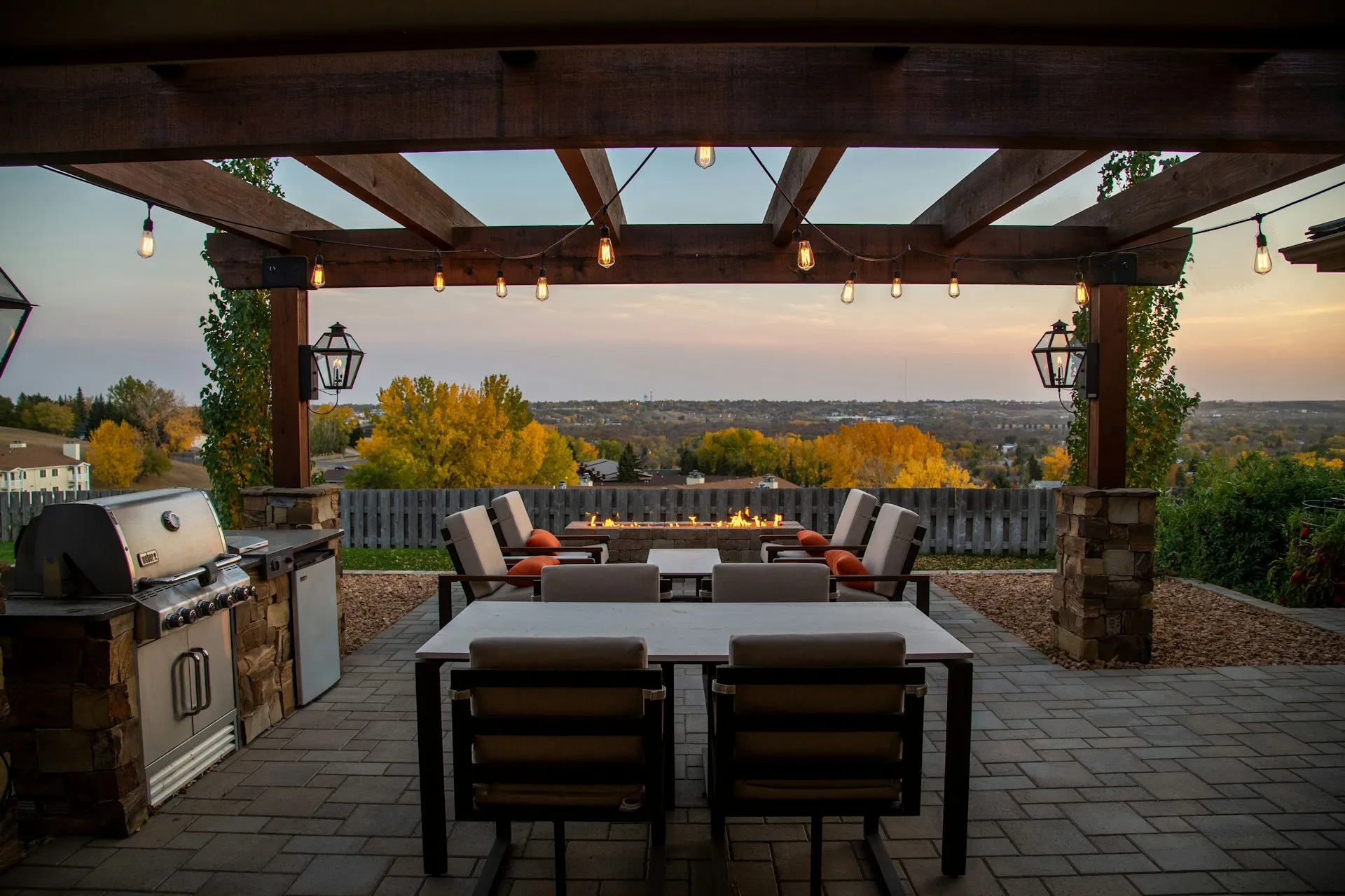 wood pergola with outdoor kitchen, dining area and fire pit overlooking backyard view