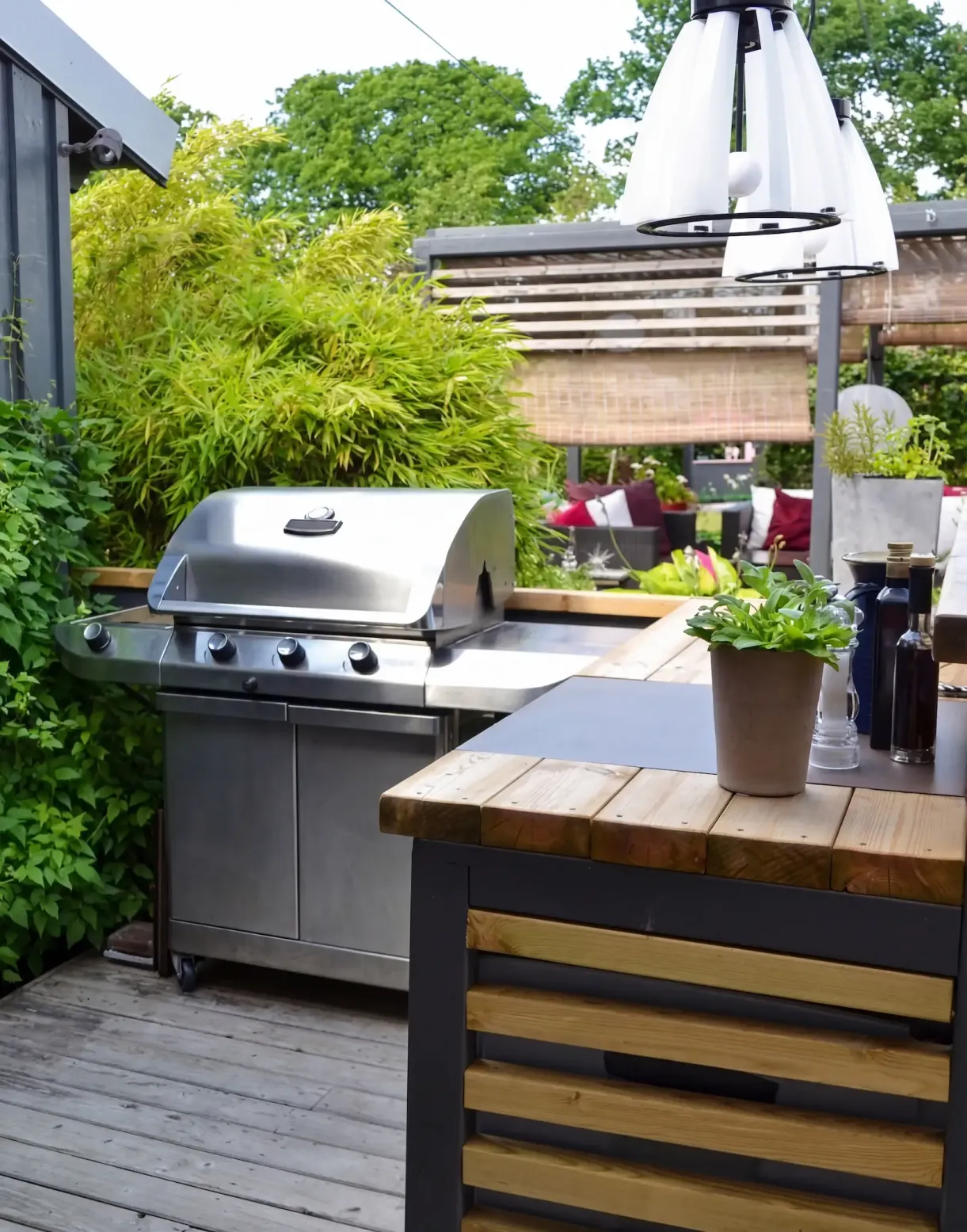 backyard outdoor kitchen with grill, wooden deck, countertop and greenery around