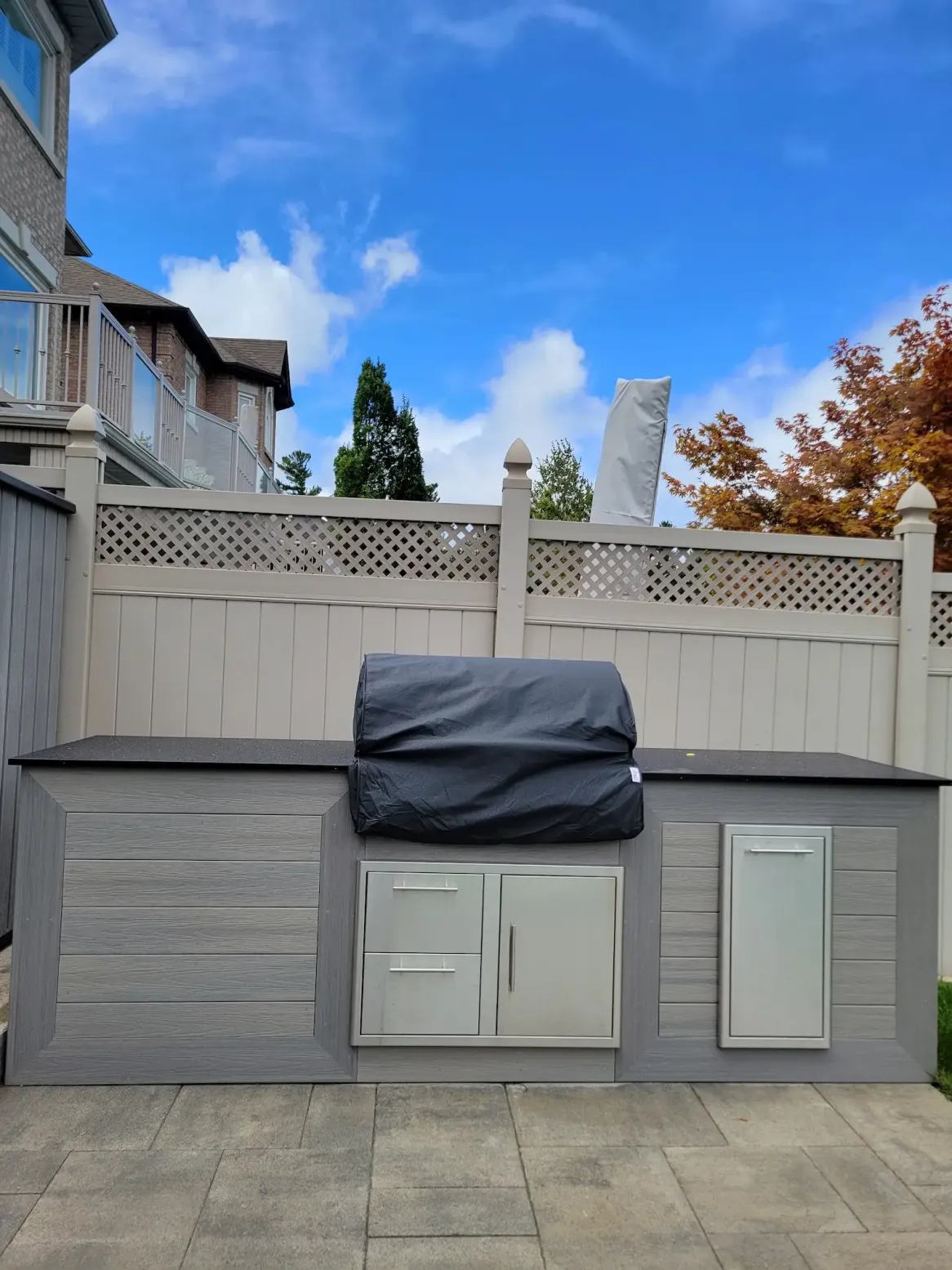 outdoor kitchen with built-in grill, storage cabinets and stone patio in backyard