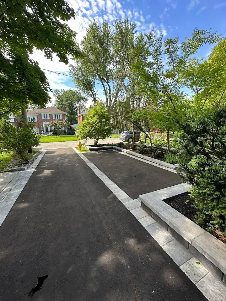 extended asphalt driveway with interlocking paver borders and added parking space in landscaped front yard