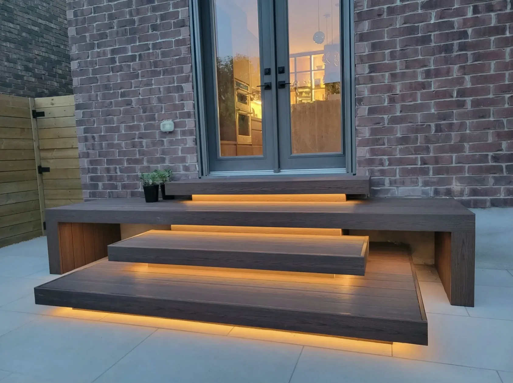 modern wood deck steps with built-in LED lighting leading to backyard patio door