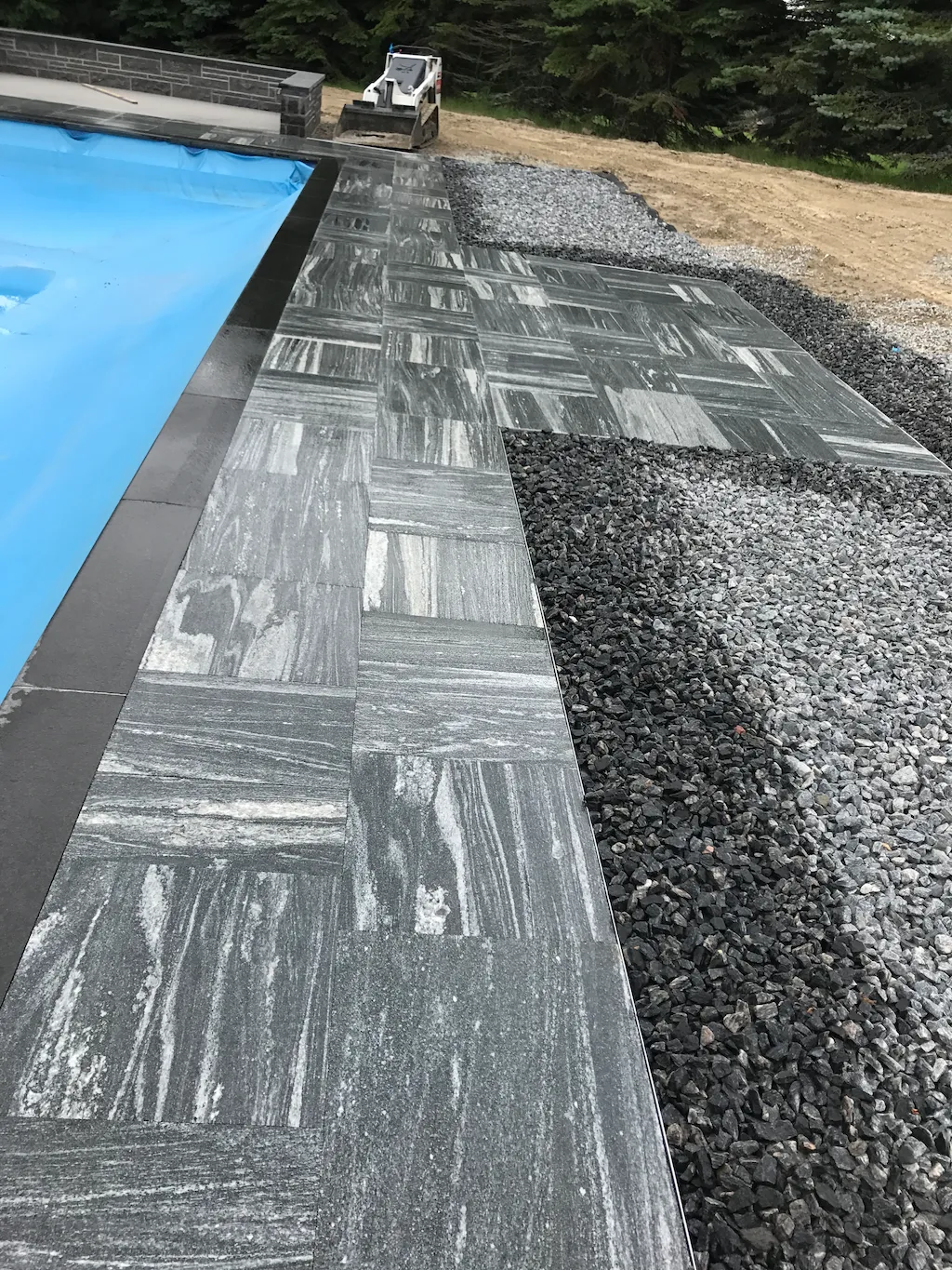 modern pool deck with gray stone pavers, clean edge coping, and decorative gravel landscaping
