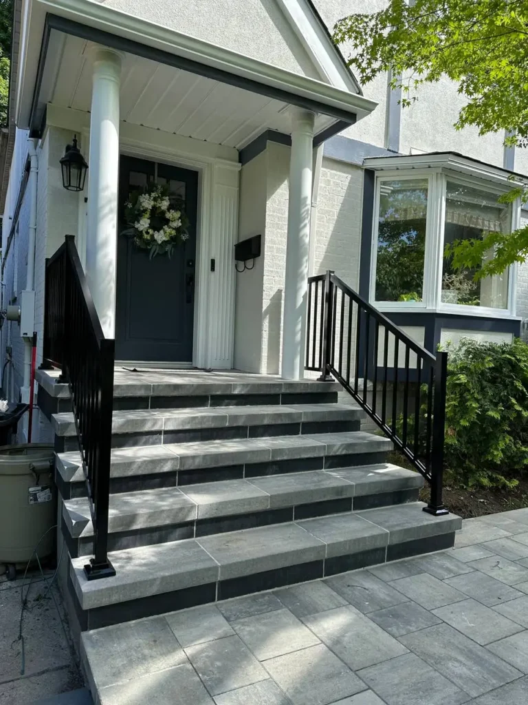 front entrance steps with interlocking stone black railing and clean residential design