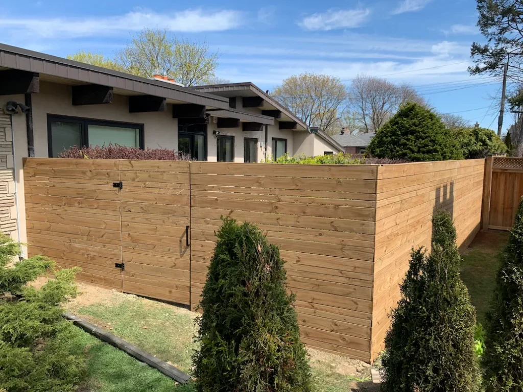 horizontal wood privacy fence enclosure with single gate around backyard space