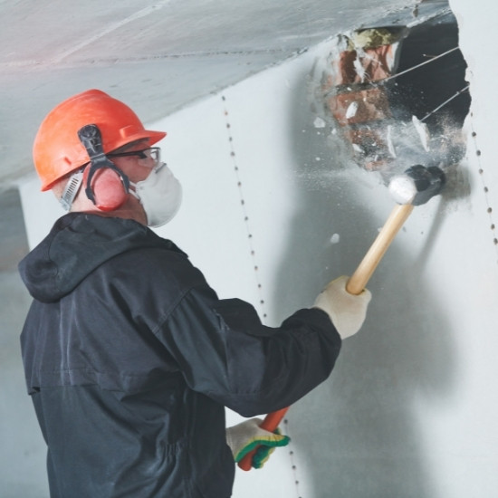 Demolition contractor breaking down drywall.