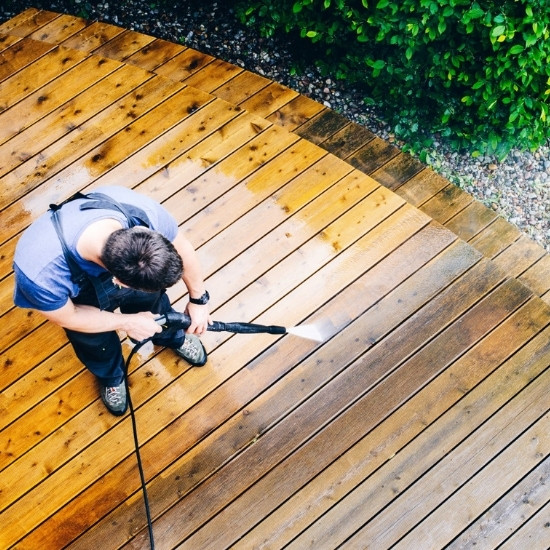 Power washing and sealing contractor washing a wood deck.