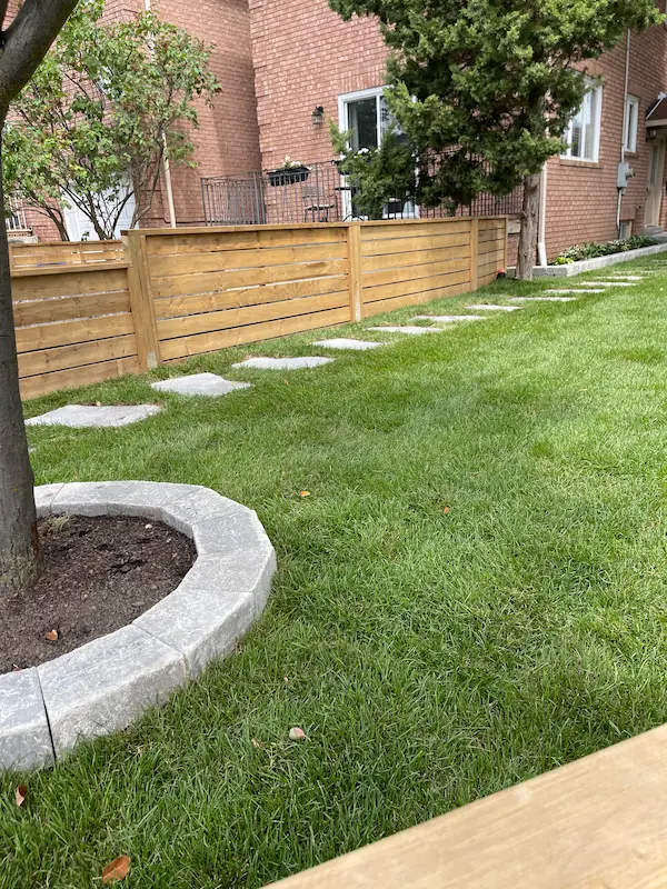 Residential landscape by Oaks with lawn, fence, and stepping stones