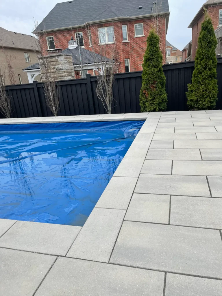 modern backyard pool with interlocking paver deck, clean edges, and fenced residential landscape