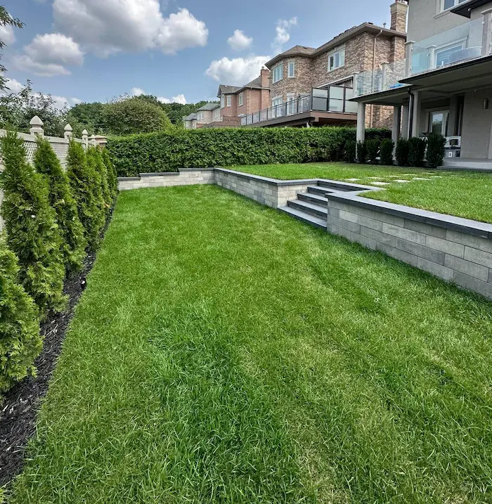 Backyard lawn and tiered retaining walls by Oaks, image by OAKS Home Services