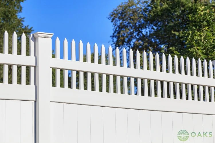 White vinyl privacy fence with decorative picket top against blue sky