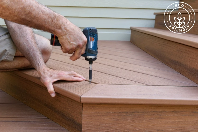 Man installing composite deck boards with power drill on eco-friendly outdoor decking steps