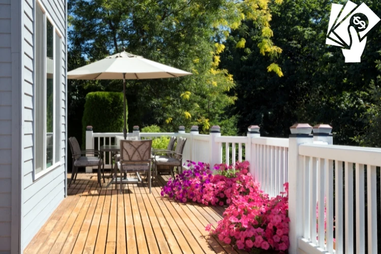 Sunny backyard deck with dining set, patio umbrella, white railing, and vibrant pink flowers