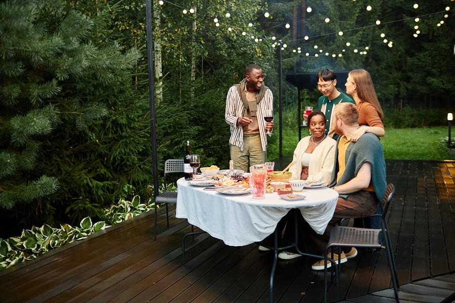 Friends enjoying an evening gathering on a professionally built backyard deck with string lights, showcasing added home value and outdoor living space