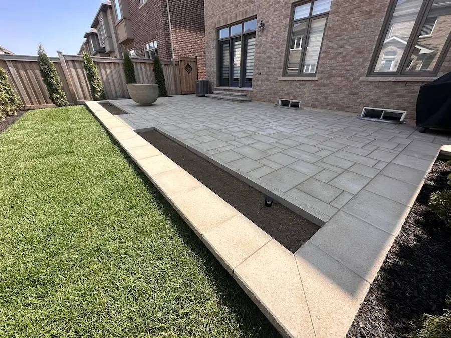Modern interlocking stone patio with raised border and clean edge detailing in Toronto backyard