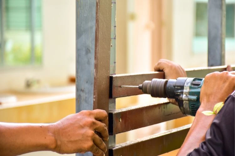 Close-up of fence installation using drill on metal privacy fence panel