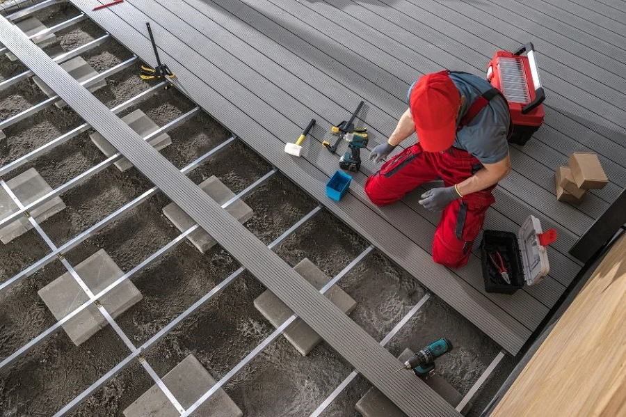 Professional deck builder installing composite decking boards over a reinforced subframe to enhance home value and durability
