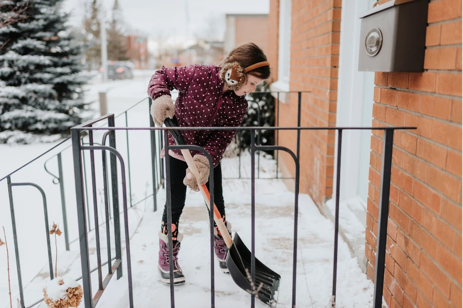 Clearing snow from walkway near home to protect landscaping and hardscapes in winter