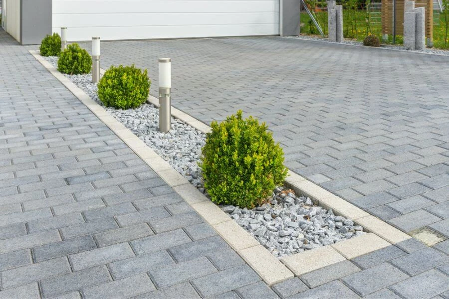 Modern interlocking stone driveway with decorative border and landscape lighting