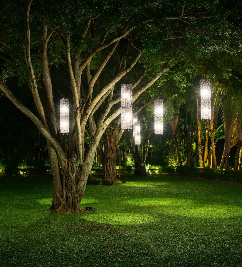 Outdoor garden with decorative hanging lanterns from tree branches at night