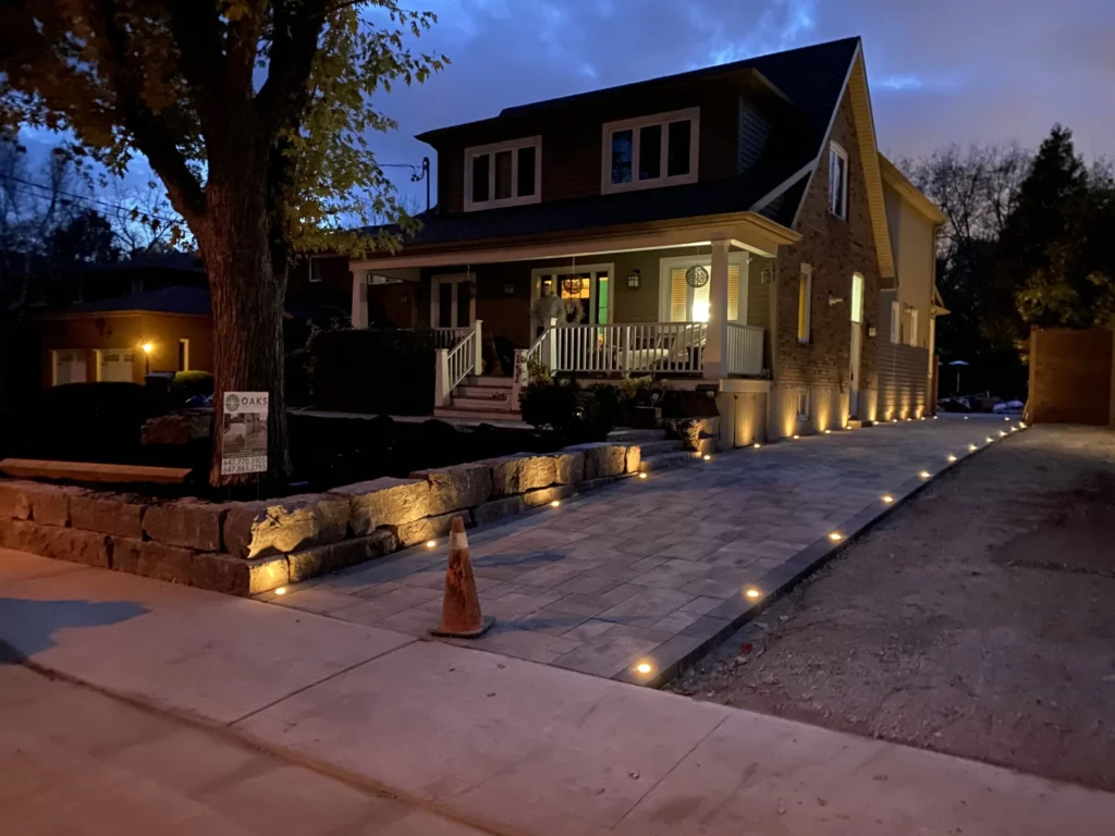 Driveway with integrated lighting and raised stone retaining walls at dusk