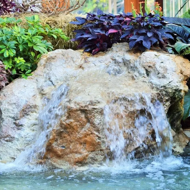 Stone water feature installed in a home's backyard, image by OAKS Home Services